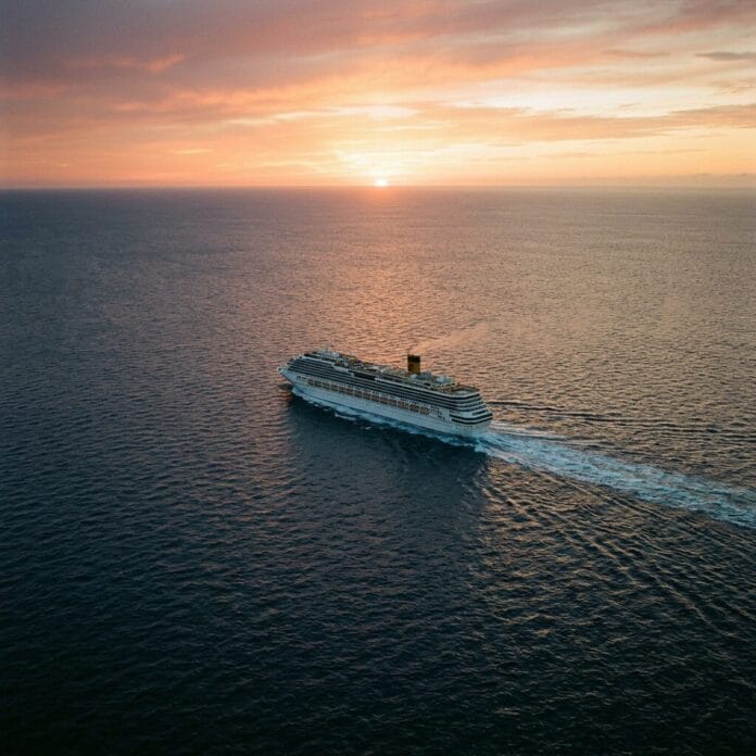 Cruise ship sailing on the ocean at sunset with colorful sky