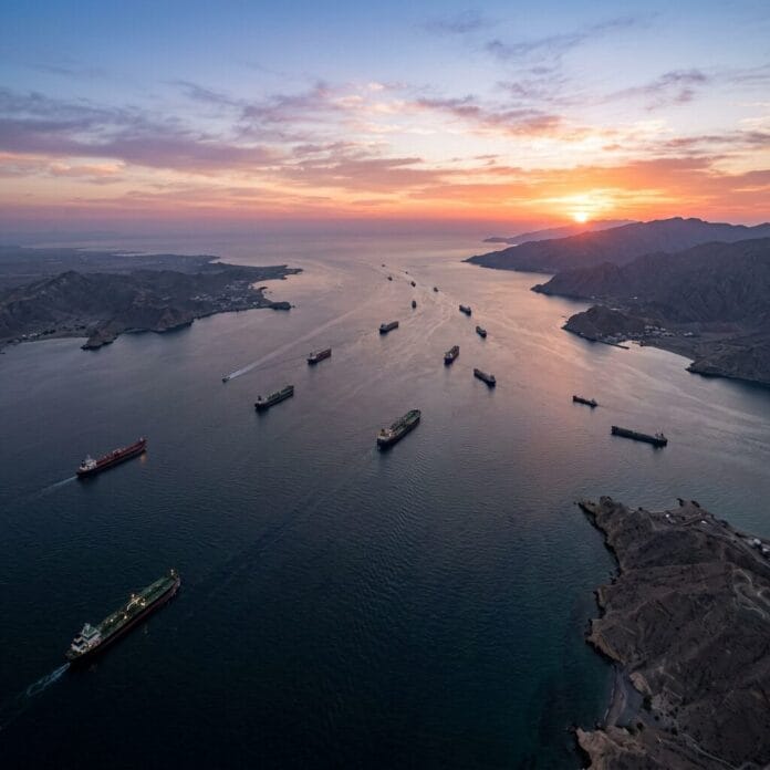 Cargo ships sailing in a narrow strait during sunset with mountainous coastlines